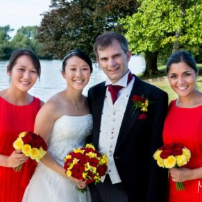 The newlyweds & their bridesmaids smile for the camera in front of the River Thames at their Bisham Abbey summer wedding