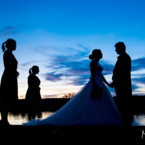 Sunset silhouette pose of the newlyweds with their bridesmaids beside the River Thames on a glorious summer's day at Bisham Abbey