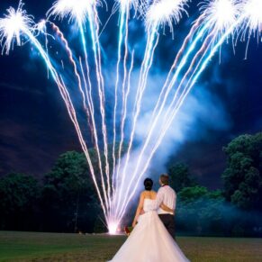 Fireworks illuminate the sky whilst the newlyweds watch the colourful display at their Bisham Abbey wedding