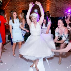 Photography of the bride loving the party vibe with her energetic friends on the dance floor as she spins around to her favourite tunes at her Brocket Hall wedding in Hertfordshire