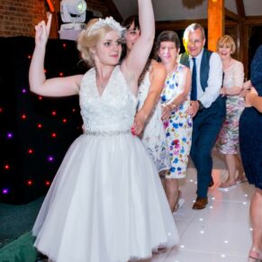 Photography of the smiling bride leads the way for the conga with her friends and family at her Brocket Hall wedding reception in Hertfordshire