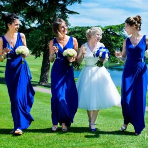 The bride walking with her bridesmaids on the lush green lawns