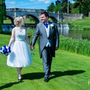 The bride and groom walk beside the river on the estate