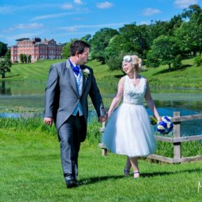 The newlyweds walking through the estate with the main house and lakes off in the distance