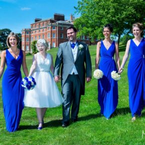 Photography of the bridal party taking a stroll with the main house off in the distance at this Brocket Hall wedding in Hertfordshire