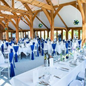 Photography of the stunning blue themed barn wedding interior with gorgeous sunlight streaming through the windows at Brocket Hall