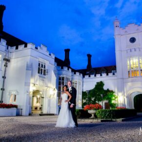 The wedding newlyweds captured dramatically at dusk in the entrance courtyard at Danesfield House Hotel