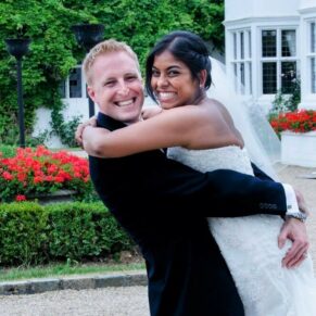 A smiling hug and embrace from the wedding newlyweds at the front of Danesfield Hotel