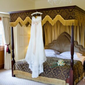 The bride's gown hung up on the four poster bed in the stunning bridal suite
