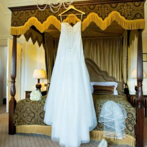 The bride's gown hanging on the four poster bed in the stunning bridal suite