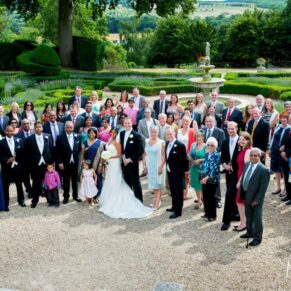 Big wedding group shot captured from the terrace overlooking the stunning gardens and distant views at Danesfield House