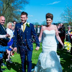 The newlyweds dash through the colourful confetti aisle at their Dorton House summer wedding