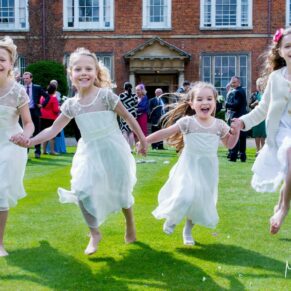 The giggling flower girls dashing through the gardens and running towards the camera at this Dorton House wedding reception