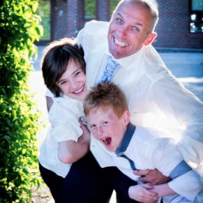 A dad and his two sons larking around and play fighting at this Dorton House wedding reception