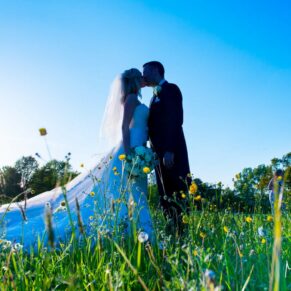 The silhouetted newlyweds enjoy a kiss in the wildflower meadow at their Dorton House wedding in Buckinghamshire
