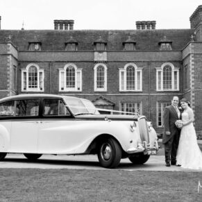 The newlyweds with their gorgeous wedding car at the front of Dorton House