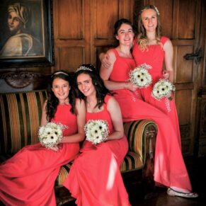 The vibrantly coloured bridesmaids really stand out in this oak panelled room as they sit on a sofa