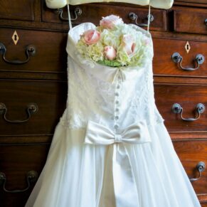 The bride's gown and bouquet hang from a fabulous antique tall boy