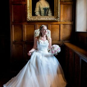 An elegant window lit portrait of the bride looking away from the camera in the Great Hall