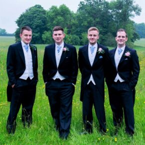 The groom and the lads pose for a formal picture in the spring meadow