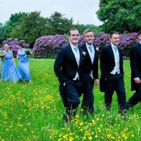 Natural shot of the bridal party walking through the spring meadow