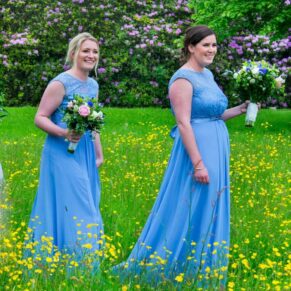The bridesmaids walking through the flower meadow as they depart the church