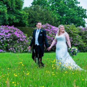 The newlyweds strolling through the meadow grasses as they leave the church on the estate