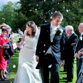 The smiling newlyweds walking through the colourful confetti aisle