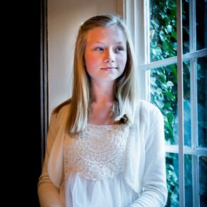 Window lit portrait of a young bridesmaid looking very elegant