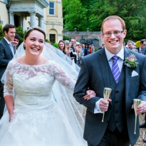 The newlyweds dash through their confetti aisle with big smiles on their faces