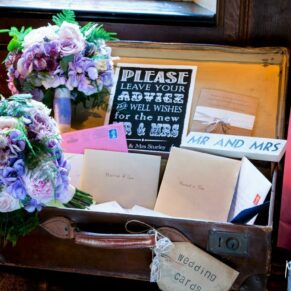 Colourful bouquets and cards arranged in a vintage suitcase in the Great Hall