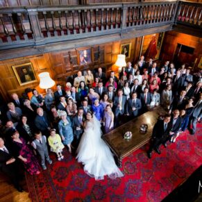 Big group wedding pose captured from the balcony in the Great Hall to showcase the wow interiors