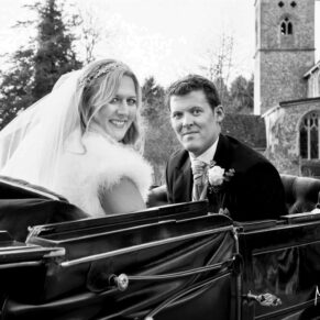 The smiling bride and groom in their open top carriage soon after their winter marriage ceremony