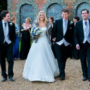 The bride casually walking along with the lads in the grounds during the drinks reception
