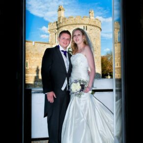 Harte and Garter wedding photography - the newlyweds pose in a doorway with Windsor Castle behind