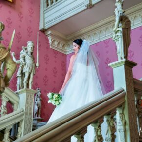 Hartwell House wedding photography - the bride poses for a photo on the staircase