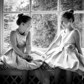 Giggling flower girls sat in a feature window captured in silhouette at Hartwell House wedding