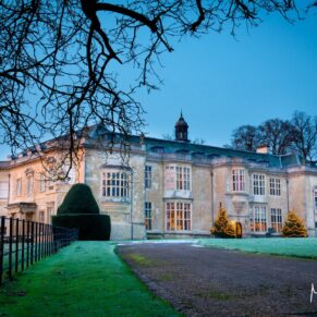 The hotel exterior captured through the trees just before sunrise at Hartwell House