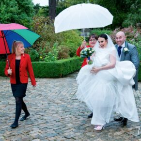 Who cares if it rains - the smiling bride arrives for her Hartwell House wedding under a brolly!