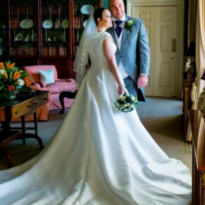 The newlyweds look out of the window surrounded by the grand interiors of the main building at Hartwell House