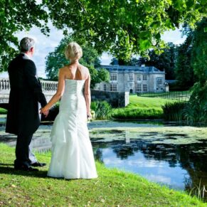 Hartwell House wedding photography - the newlyweds look over the water towards the bridge and the property