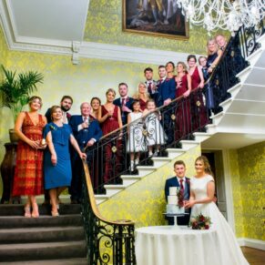 The cake cutting with the family behind on the grand staircase for this Hedsor House formal pose