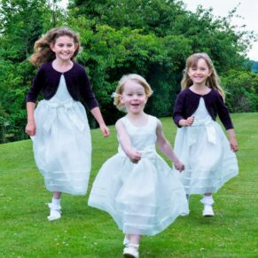 The giggling flower girls running through the gardens towards the camera