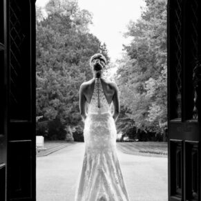 The bride in the main doorway to the house looking far off into the distance
