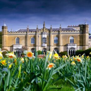 The Grade I listed property under a stormy grey sky with spring daffodils filling the foreground at this spring marriage