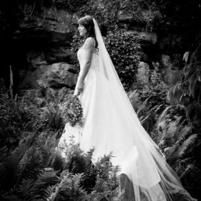 The bride placed up on large rock for a dramatic pose in the Secret Garden at The Dairy on the Waddesdon Estate