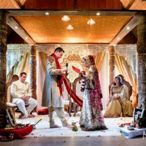 Colourful Asian wedding ceremony in progress in the West Hall at The Dairy on the Waddesdon Estate