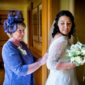 Mum helps the bride with the last few adjustments to her gown