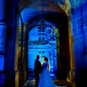 Floodlit silhouette pose of the bride and groom at Waddesdon Manor through the large entrance archway