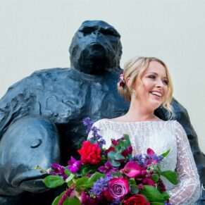 The smiling bride strikes a relaxed pose in front of the giant gorilla at Windmill Hill on the Waddesdon Estate